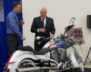 Ray Sorensen III (Left) and Iowa Lottery CEO Terry Rich unveil a motorcycle to be raffled-off. 