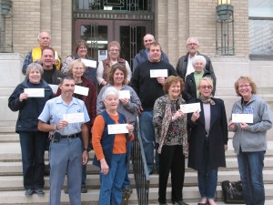 Representatives of the 14 non-profit organizations show-off their CCCF checks Friday on the steps of the Cass County Courthouse. (Ric Hanson/photo)
