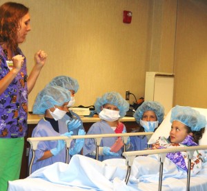 First-grader Lauren Comes pretends to get ready for a tonsillectomy under the direction of Jena Waters, R.N.(Photo submitted)