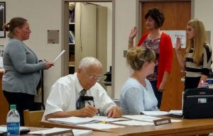 Newly elected School Board President Ali Bruckner administers the Oath of Office to Mary Beth Fast and Olivia Newberg