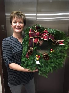 "Nancy White displays one of the holiday wreaths for sale from Xi Beta Phi members this month." (photo submitted)