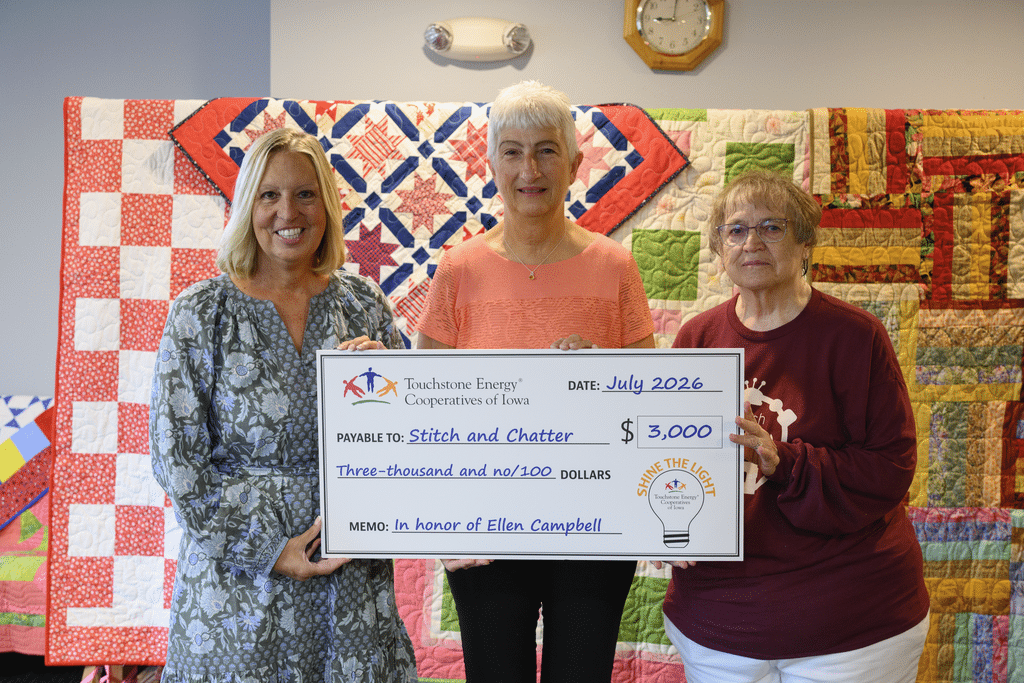 Ellen Campbell of Panora, right, accepted a $3,000 check from the Touchstone Energy Cooperatives of Iowa for Stitch and Chatter after being selected as one of three statewide winners in the Shine the Light contest. There were almost 80 entries in the contest from the rural electric cooperatives in Iowa. Making the presentation were, Cozy Nelsen, left, CEO of Guthrie County Rural Electric Cooperative, and Luann Waldo, center, who nominated Campbell and Stitch and Chatter for the honor. 